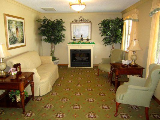 A cozy living room with a fireplace, sofas, and decorative plants.
