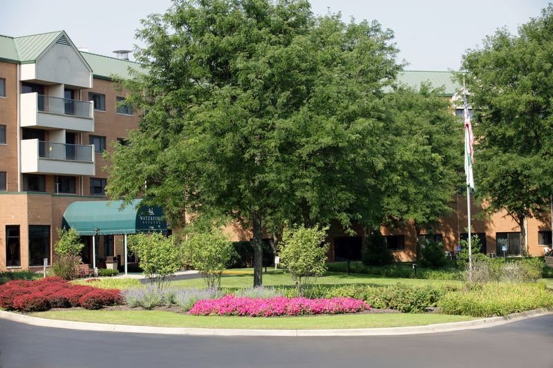 A beautiful garden area with a large tree and vibrant flowers in front of a building.