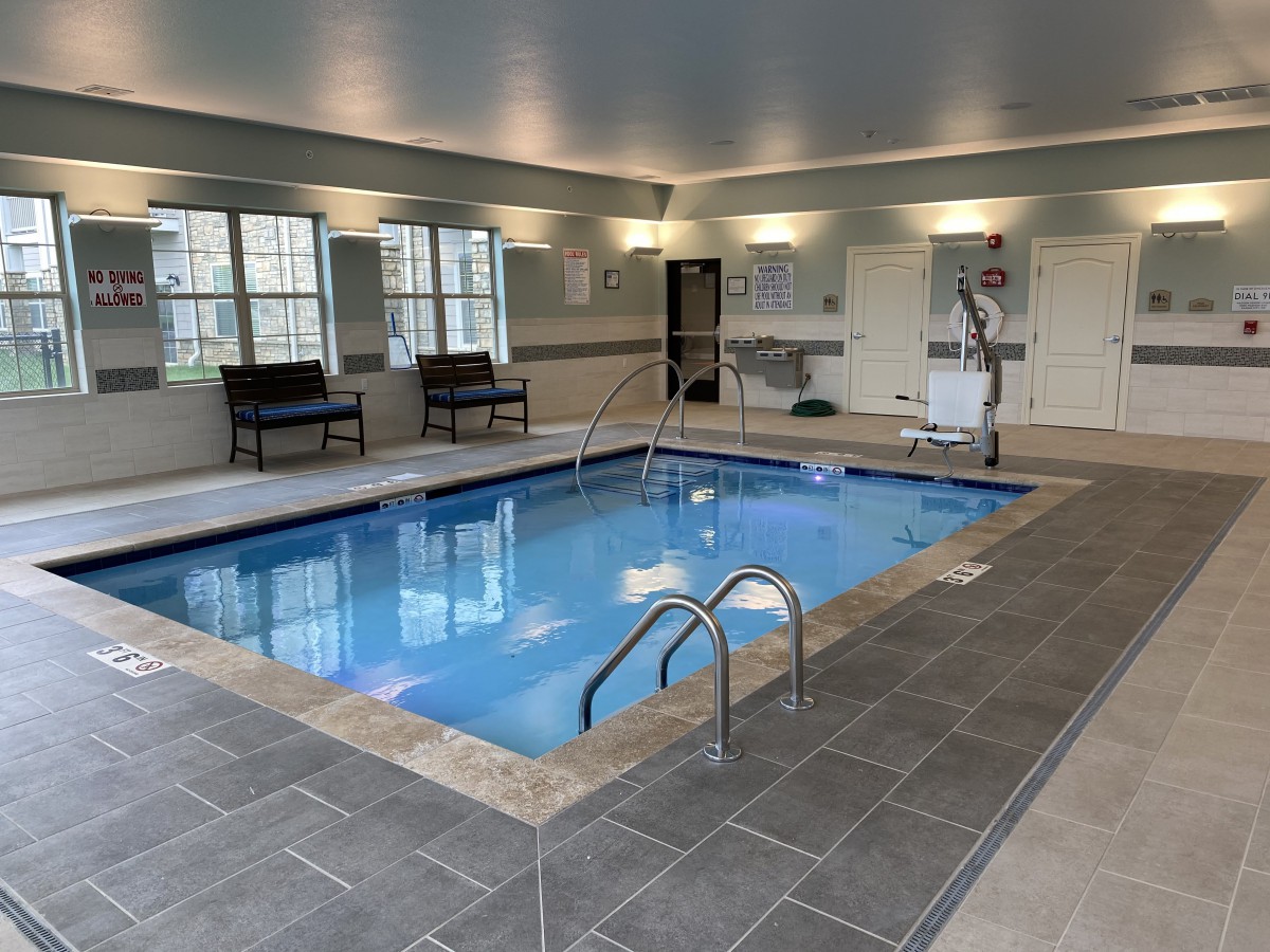 A modern indoor swimming pool with seating and bright overhead lighting.