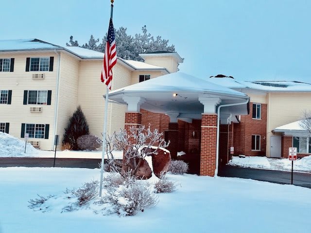 A snowy scene featuring a building with an American flag outside.