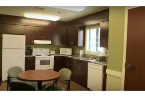A cozy kitchen interior with appliances, a table, and chairs.