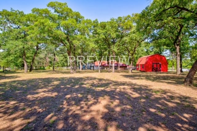 A sunny day in a park-like setting with red buildings surrounded by trees.