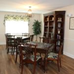 A cozy dining room with wooden furniture and a bookcase.