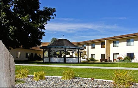 A scenic view of a gazebo and building set against a clear blue sky.