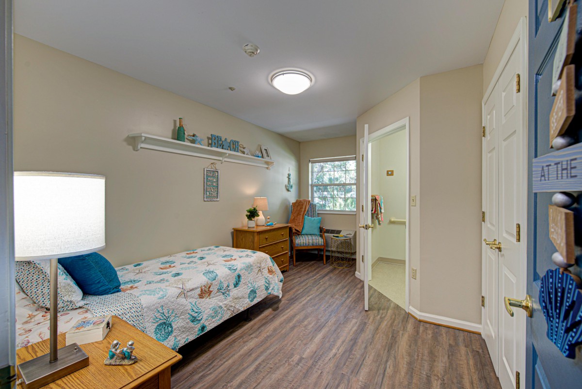 A cozy bedroom with a single bed, a wicker chair, and bright decor.