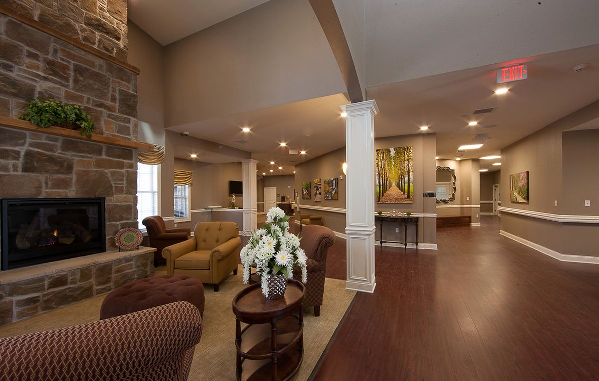 A spacious and elegantly designed living room featuring comfortable furniture, decorative flowers, and artwork on the walls.