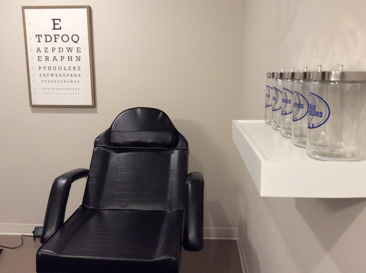 An optometrist's office with an eye exam chair and vision chart on the wall.