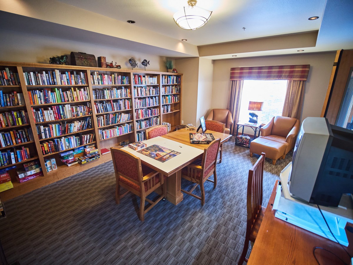 A cozy reading room with bookshelves, a table, and comfortable seating.