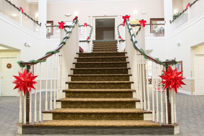 A grand staircase adorned with festive Christmas decorations, featuring garlands and poinsettias.
