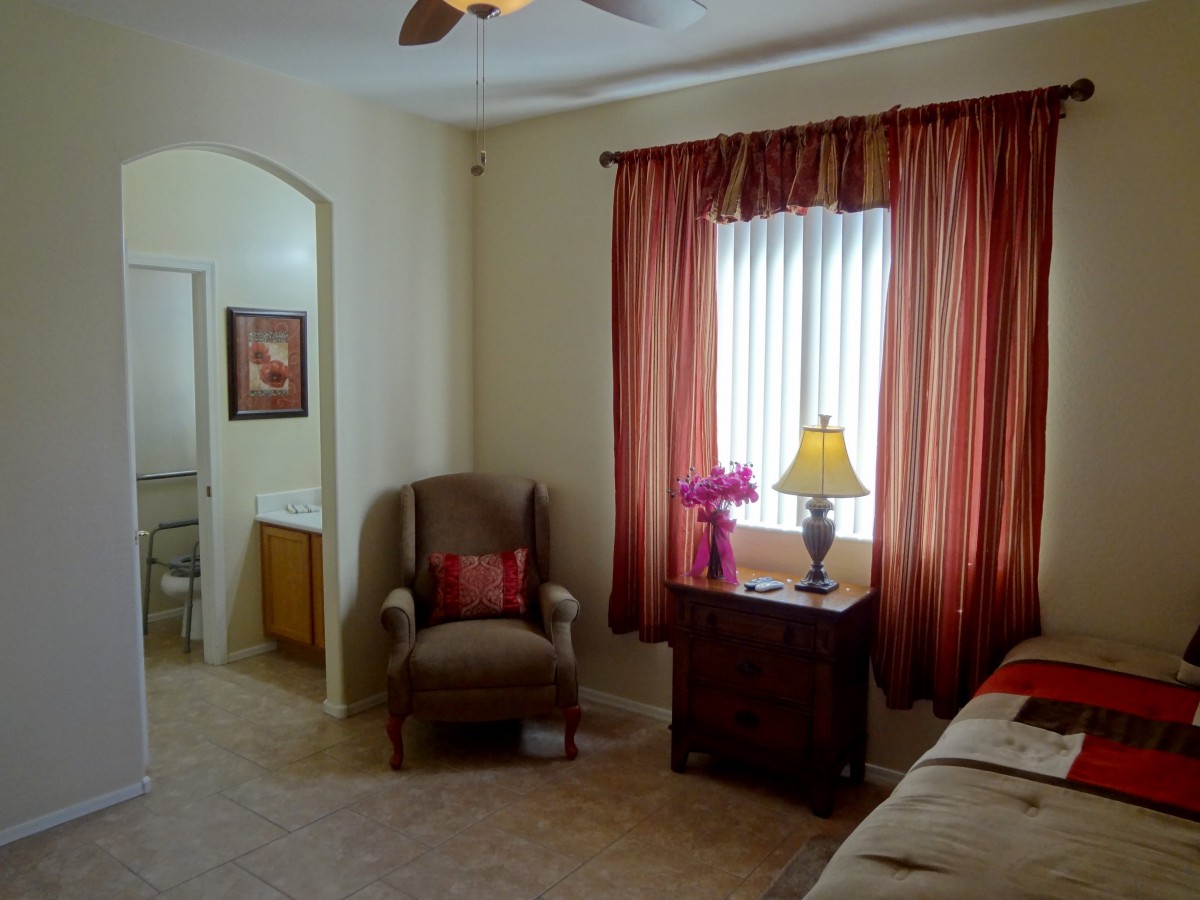 A cozy bedroom with an armchair, side table, and elegant curtains.