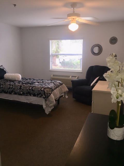A minimalist bedroom with a single bed, armchair, and simple decorations.