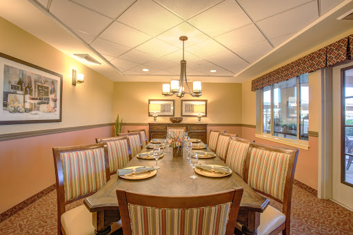 A stylish dining room featuring a long table and striped seating, illuminated by elegant lighting.