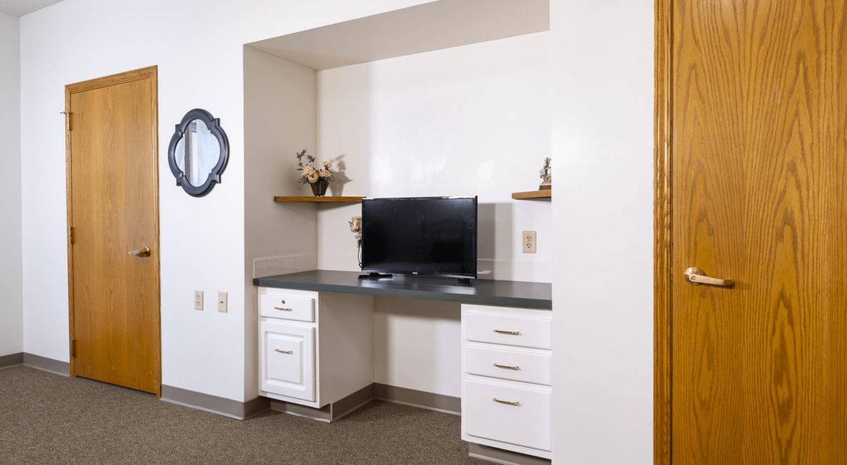 A home office setup with a desk, monitor, and shelves.