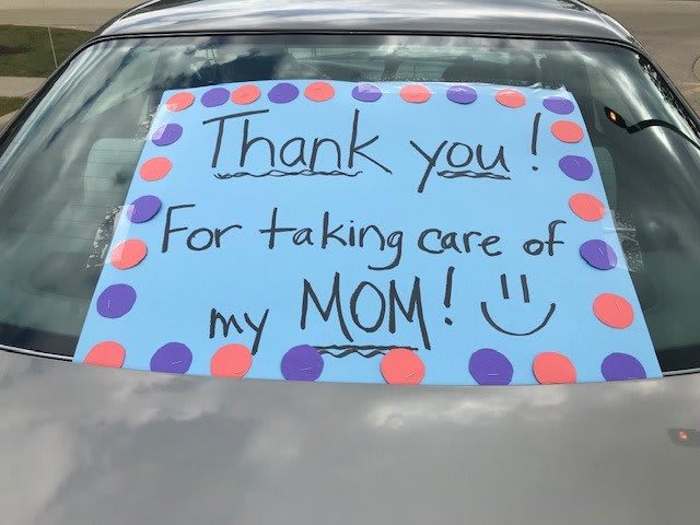 A heartfelt 'Thank You' sign displayed on a car windshield, expressing gratitude for taking care of someone's mom.