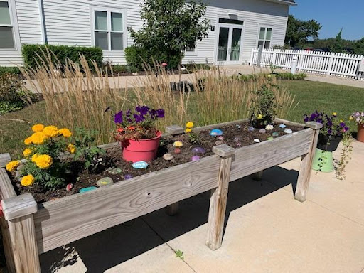 A vibrant flower garden in a wooden planter, showcasing colorful blooms and decorative stones.