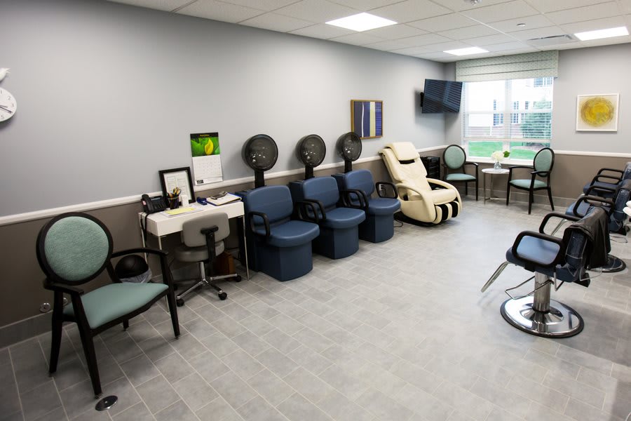 A modern salon interior with chairs, hair dryers, and a massage chair.