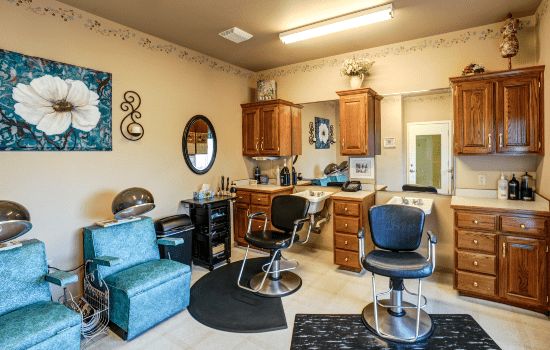 Interior view of a hair salon with styling chairs, mirrors, and cabinets.
