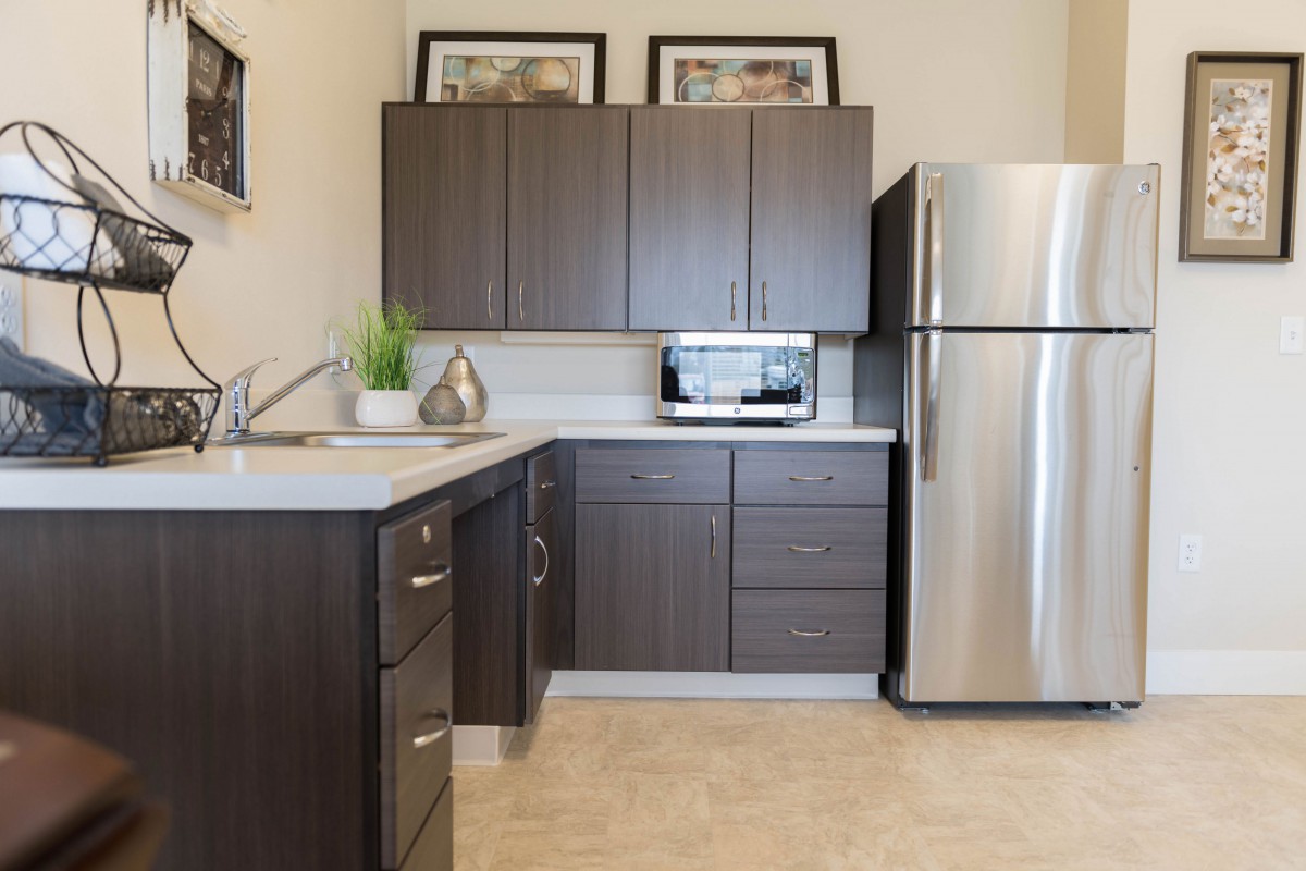 A modern kitchen with dark wood cabinets and stainless steel appliances.