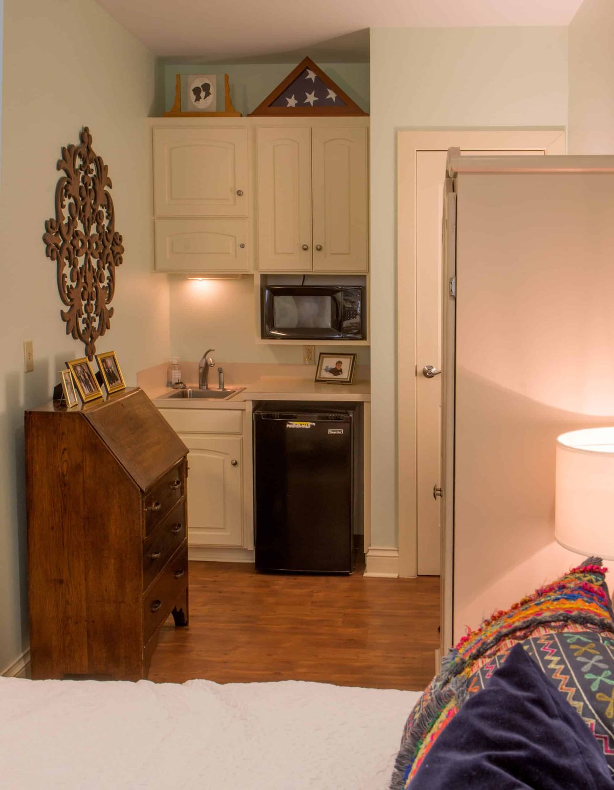 A cozy kitchenette with a microwave, refrigerator, and decorative elements in a small room.