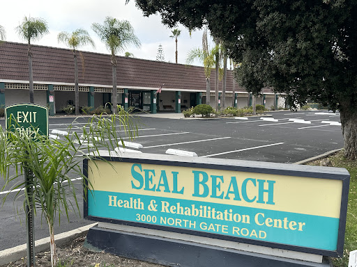 The entrance of the Seal Beach Health & Rehabilitation Center, showcasing its inviting exterior and ample parking space.