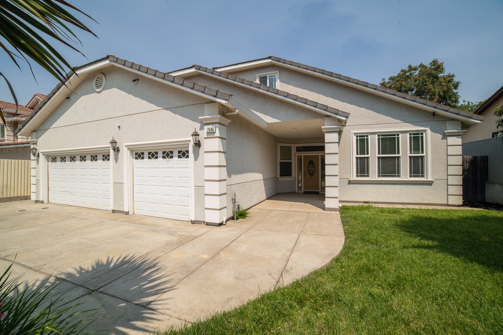 A suburban residential house with a two-car garage and a well-maintained lawn.