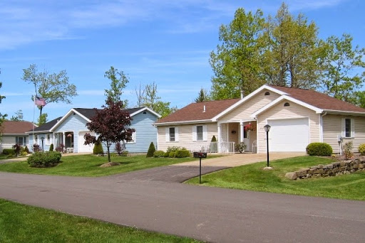 A peaceful suburban neighborhood featuring well-maintained houses under a bright blue sky.