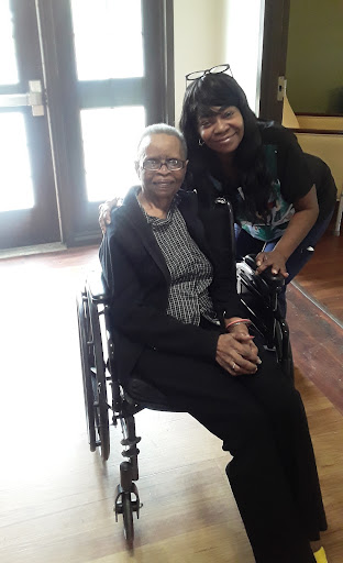 A joyful moment shared between an elderly woman in a wheelchair and her caregiver.