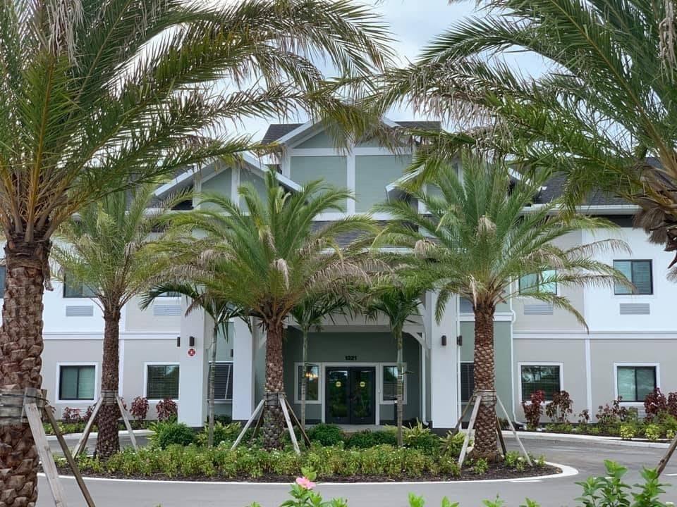 A modern building entrance surrounded by palm trees and landscaping.