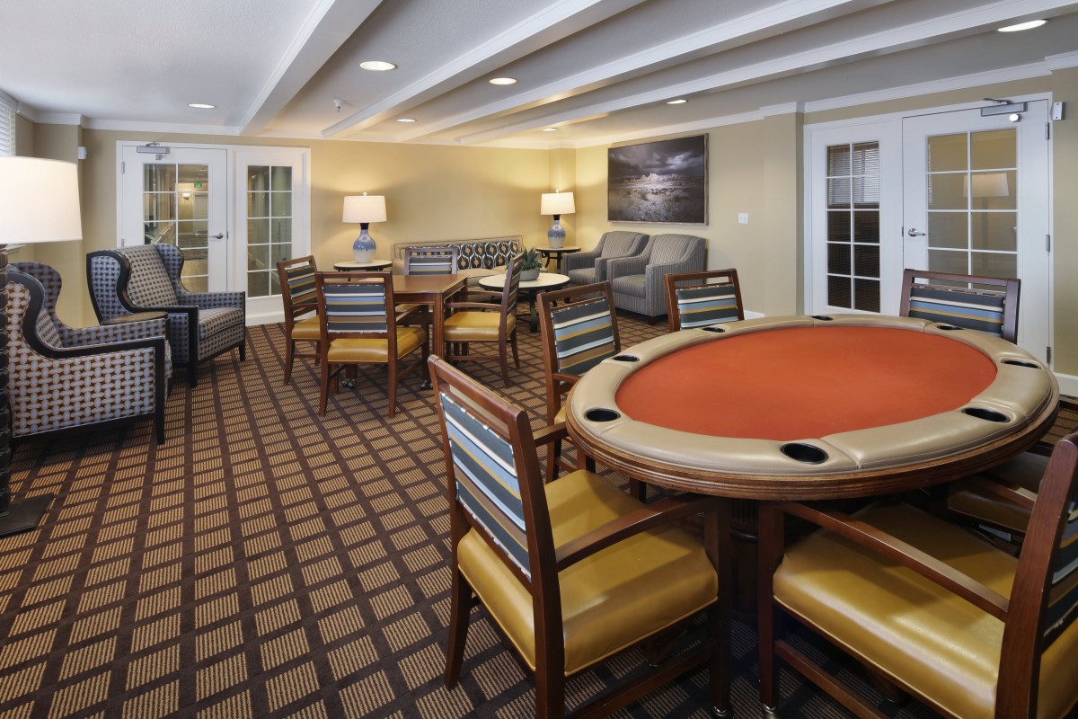 A cozy lounge area featuring a poker table, surrounding chairs, and comfortable sofas.