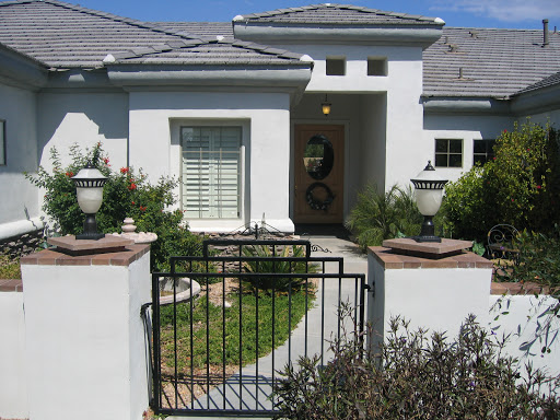 A modern house entrance featuring a black gate and well-kept garden.
