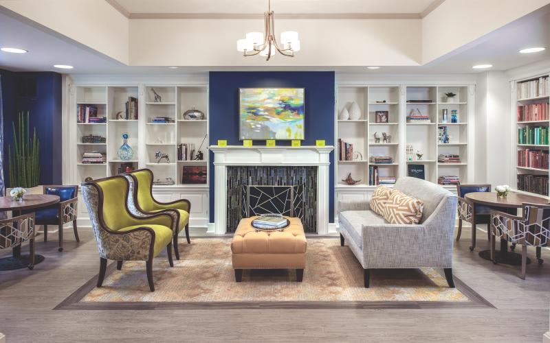 A stylish living room featuring a fireplace, modern furniture, and well-organized bookshelves.