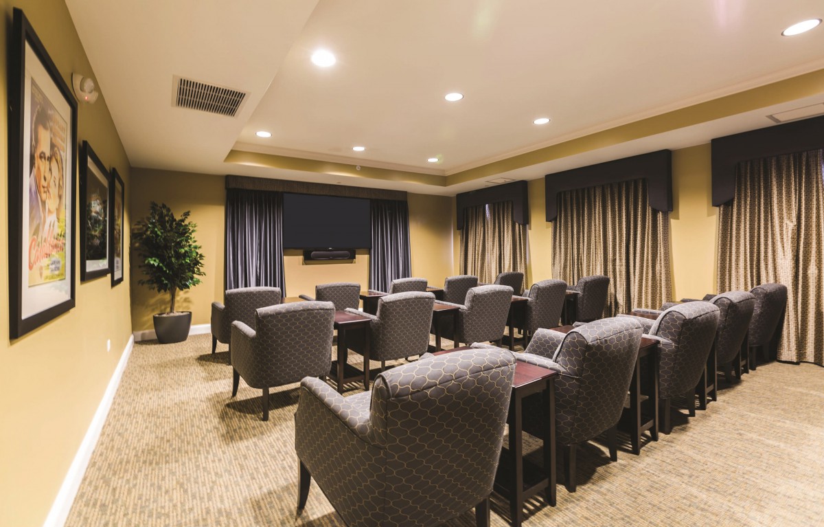 A well-furnished conference room with comfortable seating and a large television at the front.