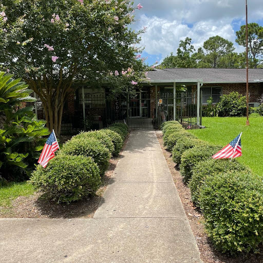 A welcoming front yard featuring neatly trimmed bushes and small American flags lining the pathway.