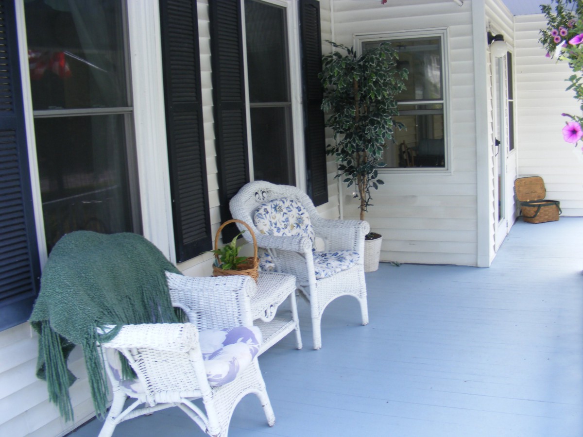 A cozy porch with wicker chairs and a potted plant, perfect for relaxation.