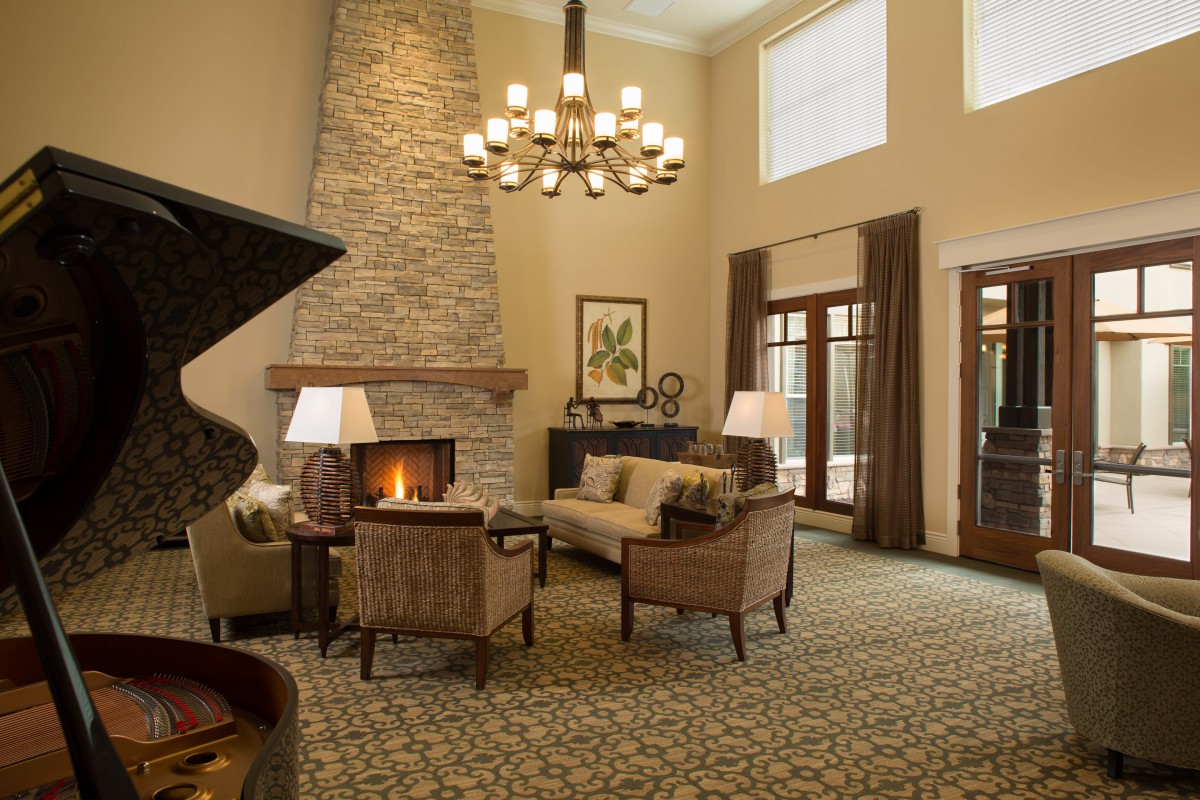 A cozy living room with a stone fireplace and elegant chandelier.