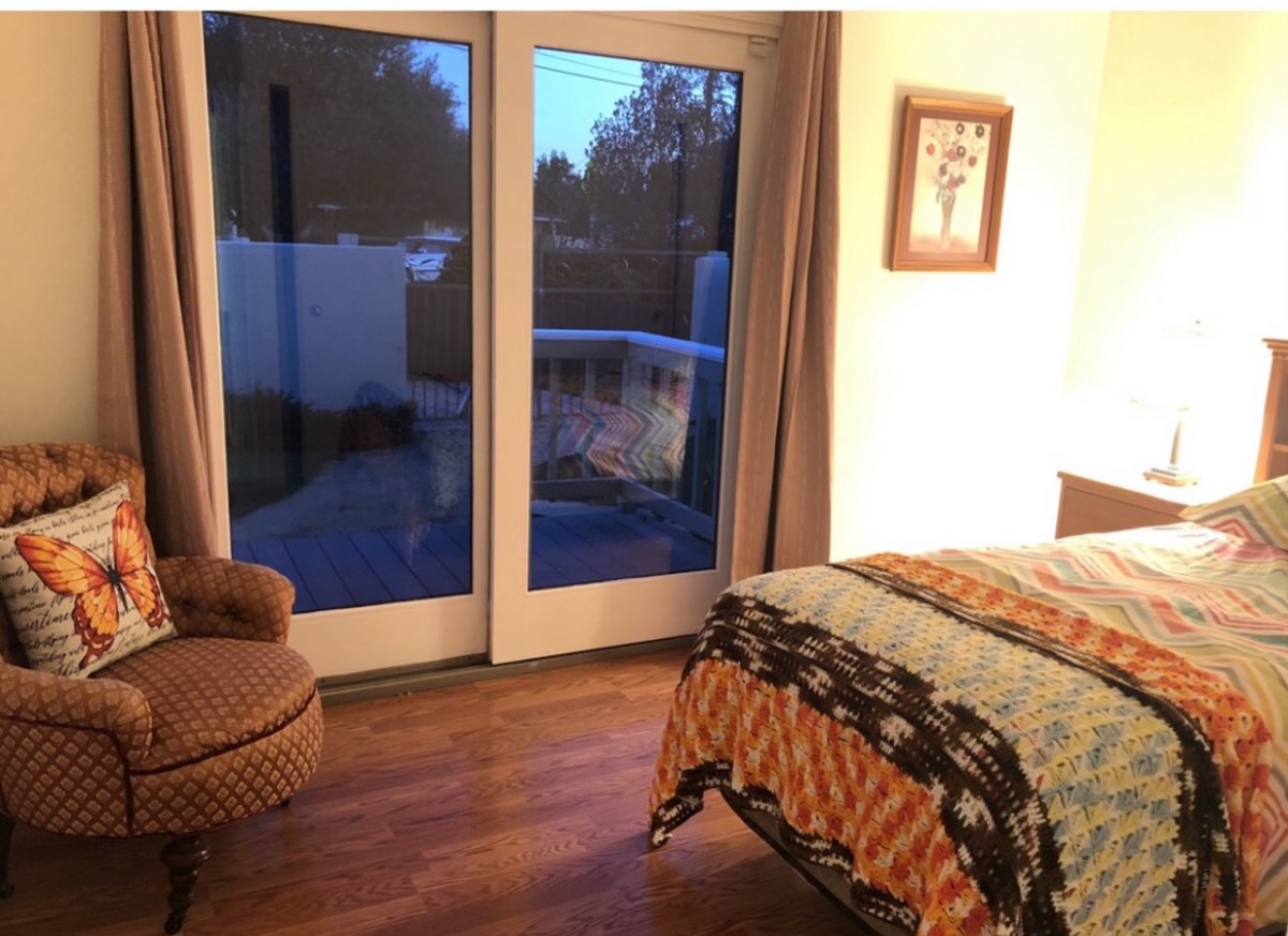 A cozy bedroom with a comfortable chair and a bed near large glass doors.