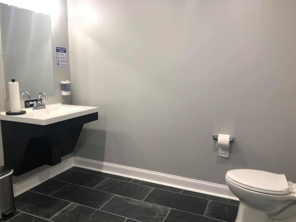 A modern, minimalist bathroom featuring a sink and toilet with tile flooring.