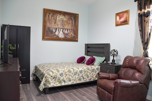A cozy and well-decorated bedroom featuring a comfortable bed, a recliner chair, and artistic wall decorations.