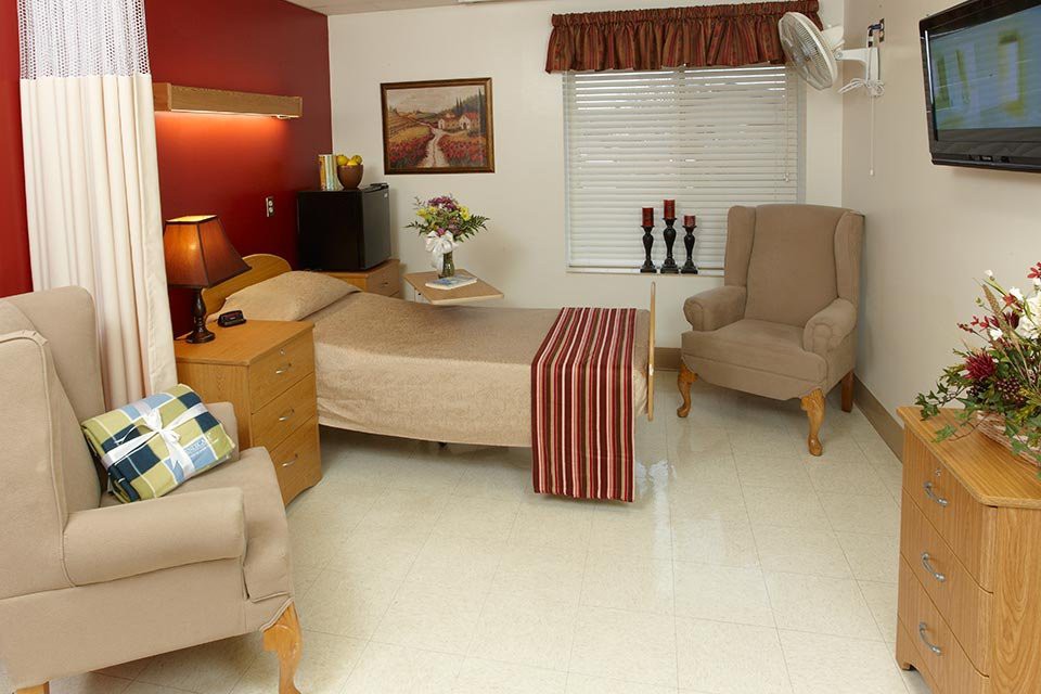 A cozy bedroom featuring a bed, armchairs, and warm lighting.