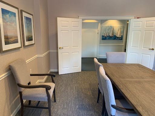 A spacious meeting room featuring a wooden table, comfortable chairs, and decorative wall art.