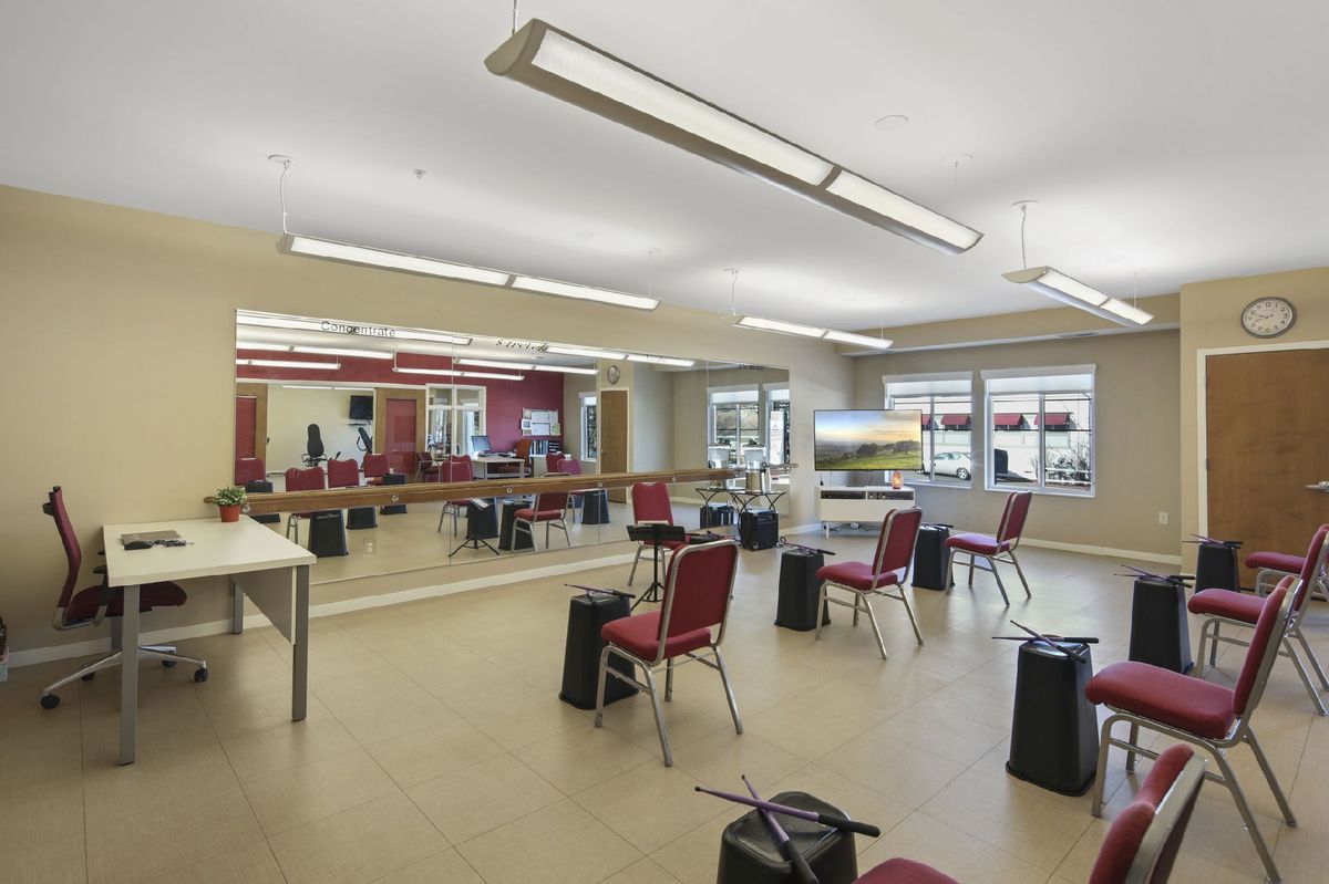 A spacious dance studio with mirrors, chairs, and ample lighting.