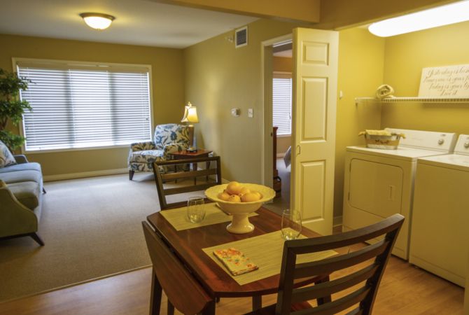 A cozy apartment interior featuring a dining area with a table and chairs, adjacent to a well-lit living room.