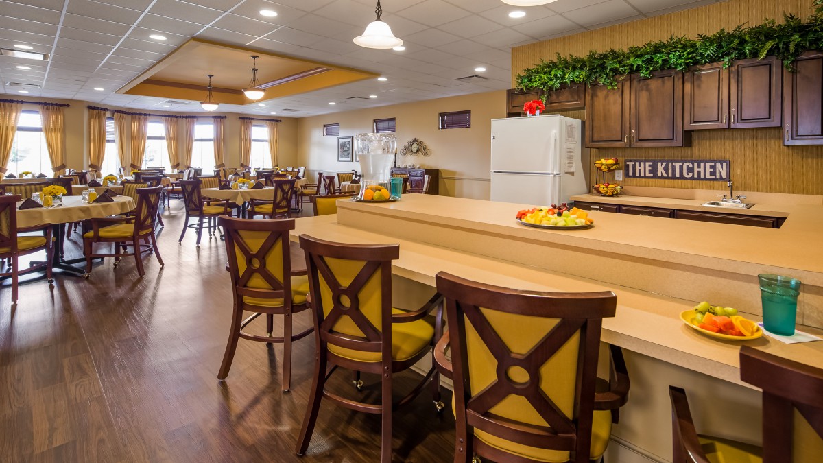 A cozy dining and kitchen area with wooden furniture and a well-lit atmosphere.