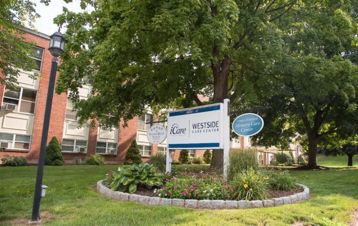 Outdoor view of a building with a sign surrounded by trees and landscaping.