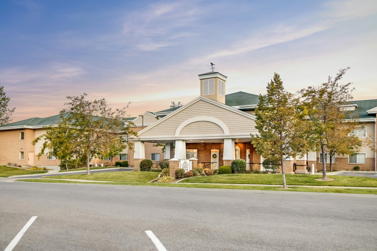 A well-maintained building surrounded by trees at sunset, with a road in the foreground.
