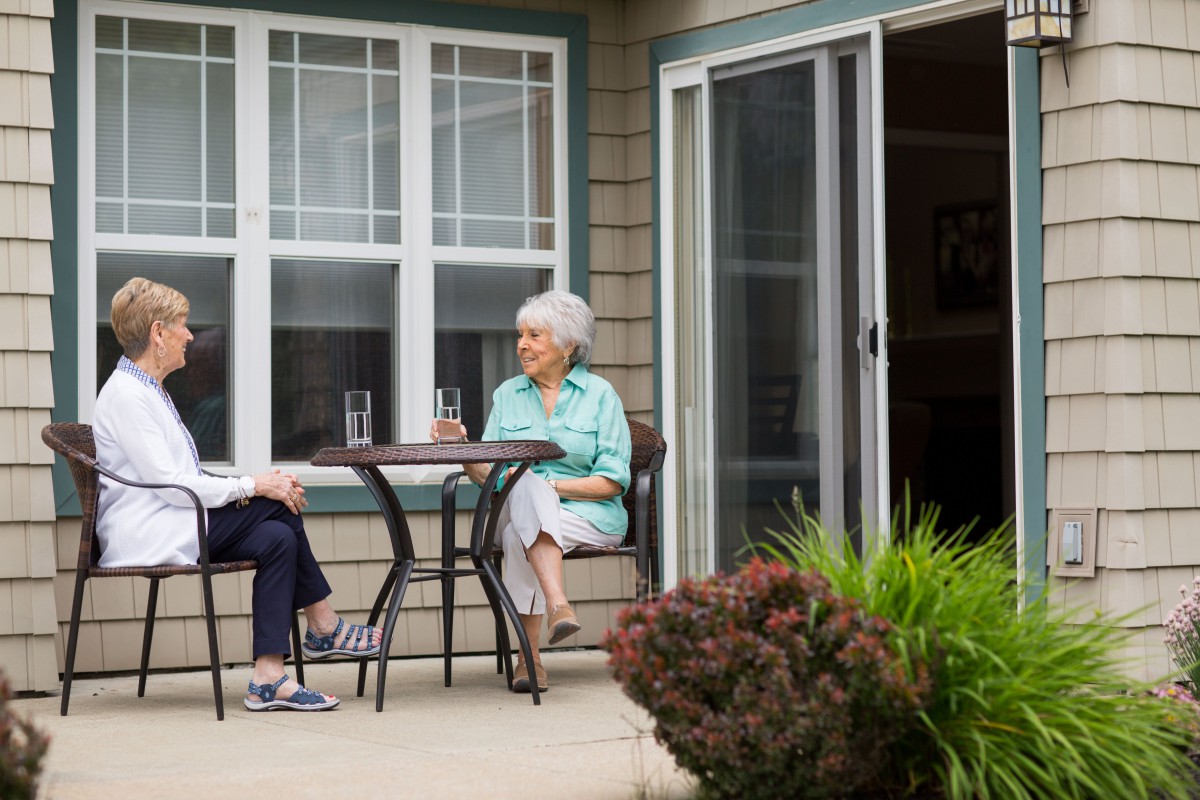 Two elderly individuals enjoying a conversation on a patio.