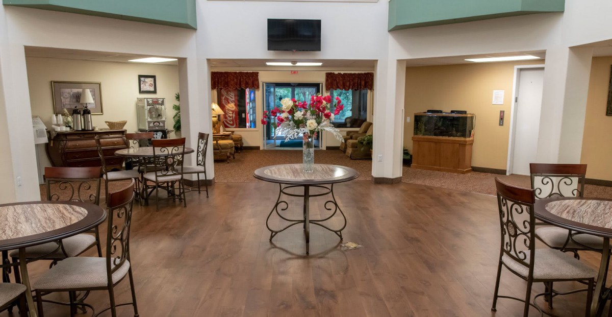 A modern lobby with a central table display featuring flowers, surrounded by seating areas.