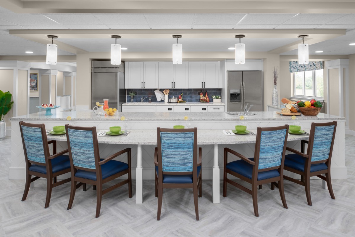 A modern kitchen with a large island, stylish chairs, and pendant lighting.