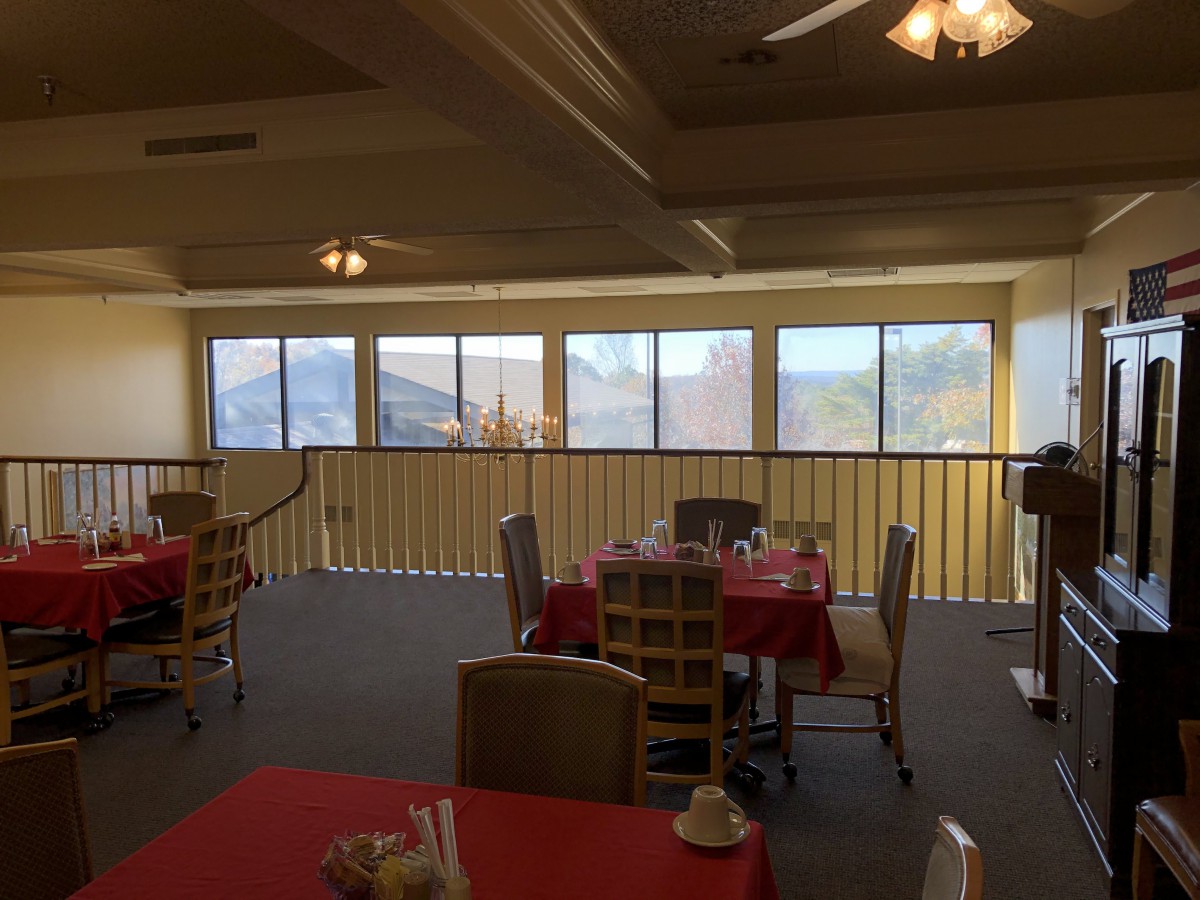 A cozy restaurant interior with red tablecloths and large windows offering a scenic view.