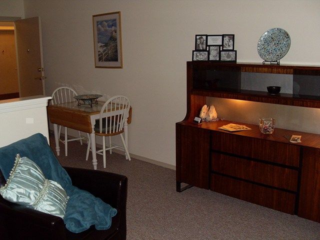 A cozy living room with a dining table and a wooden hutch displaying decorations.